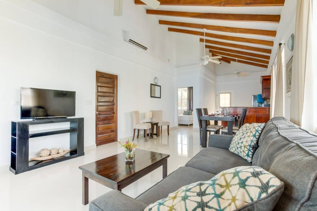 Living room with a grey couch with pillows, a wooden coffee table, and a television inside the 2 Bedroom Lagoon Bayview at Umaya Resort & Adventure