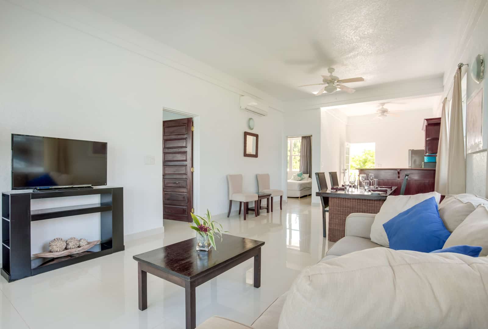 Corner view from the living room area showing a television, the kitchen, and the entrance to the master bedroom inside the 2 Bedroom Penthouse Lagoon Bayview at Umaya Resort & Adventure