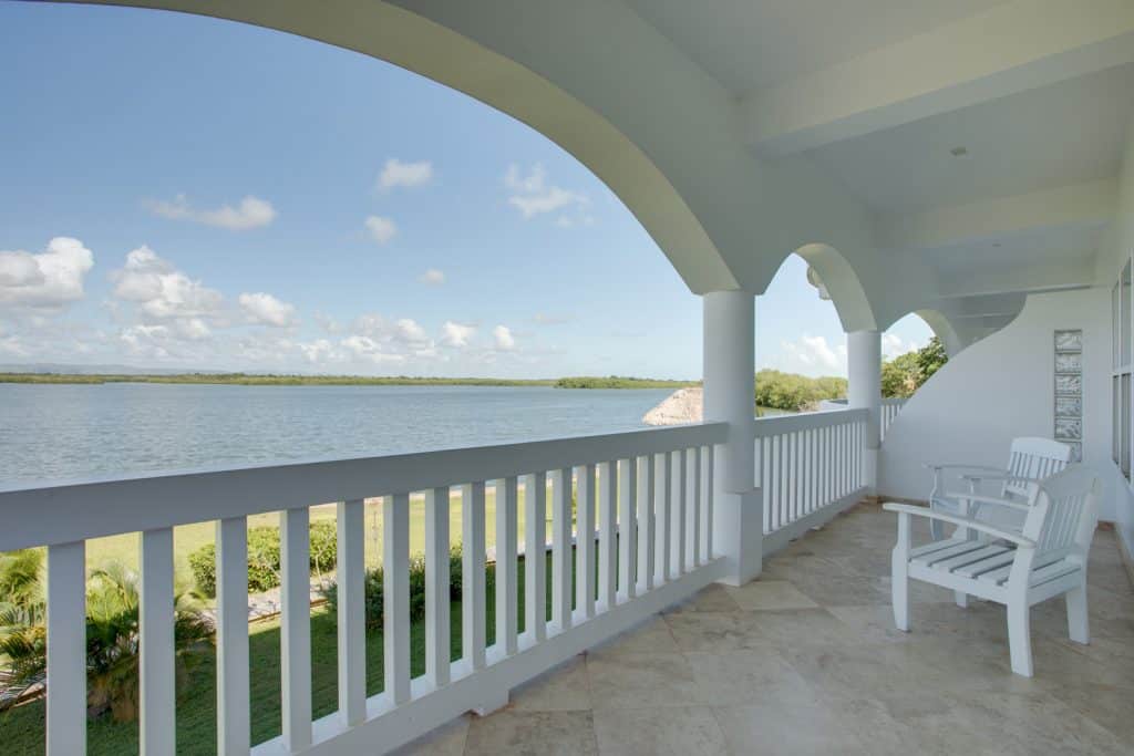 Balcony with two white wooden chairs overlooking the lagoon outside of the 2 Bedroom Penthouse Lagoon Bayview at Umaya Resort & Adventure