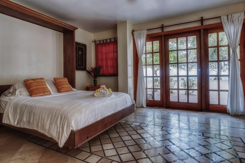 The master bedroom with a king sized bed and glass doors that open up to the beach inside the One Bedroom Beachfront Suites at The Colonial Inn