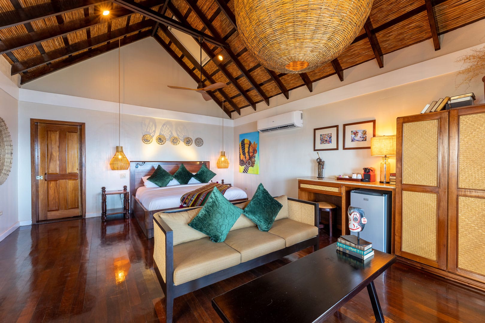 Side view of the lving room area and bed with a view of the closet and mini fridge inside the Beachfront Cottages at The Resort at Almond Beach