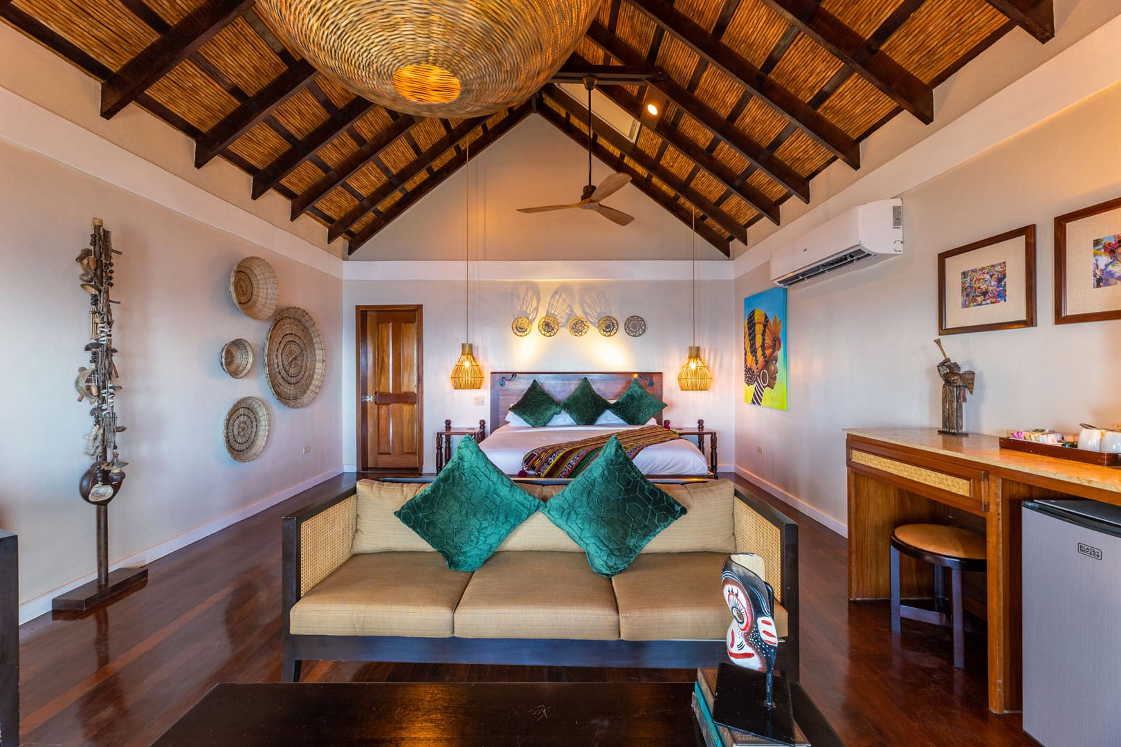 View of the living room area with a bed in the background inside the Beachfront Cottages at The Resort at Almond Beach