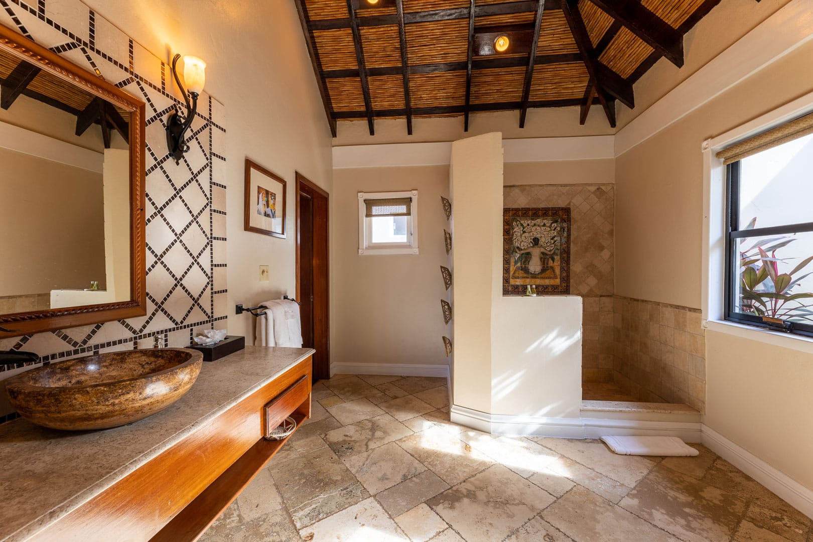 Bathroom showing a vanity mirror and sink as well as a walk in shower inside the Beachfront Cottages at The Resort at Almond Beach