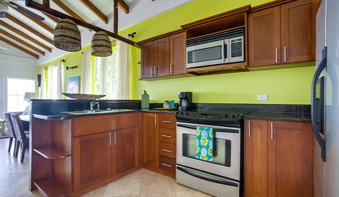 The kitchen area with wooden cabinets, a stove and a fridge inside of the 2 Bedroom Penthouse Beachfront at Umaya Resort & Adventure