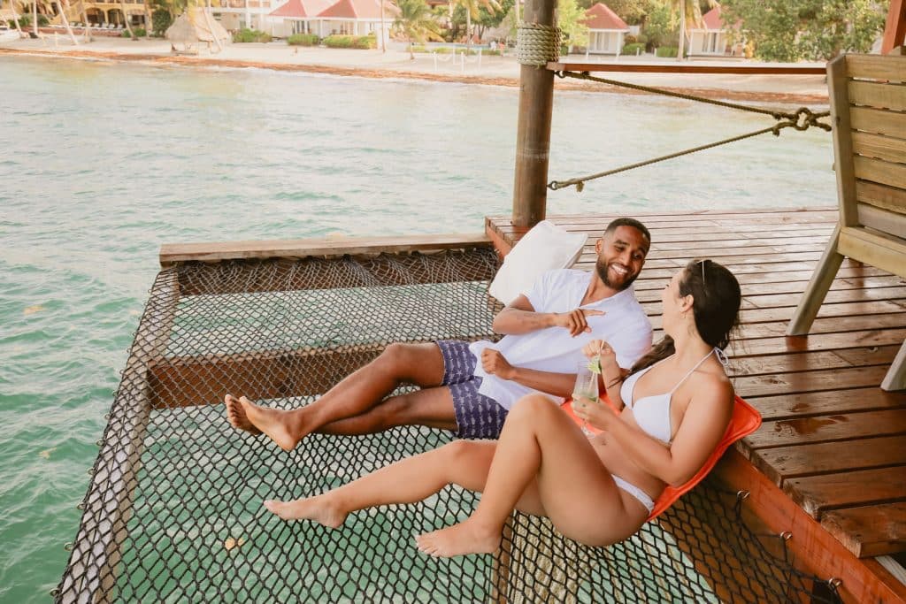 Happy young couple lying in the fishnet hammock on the Big Dock Restaurant at The Lodge at Jaguar Reef Resort