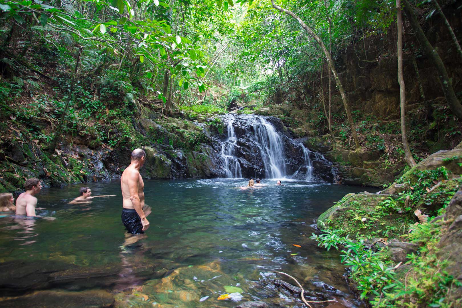 Guests swimming in the waterfall on the Jaguar Preserve Waterfall Hike at The Lodge at Jaguar Reef