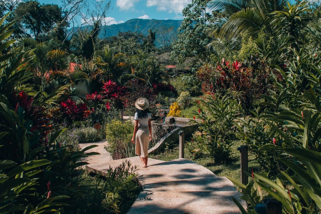 A guest walking down a pathway that is surrounded by flowers and lush greenery