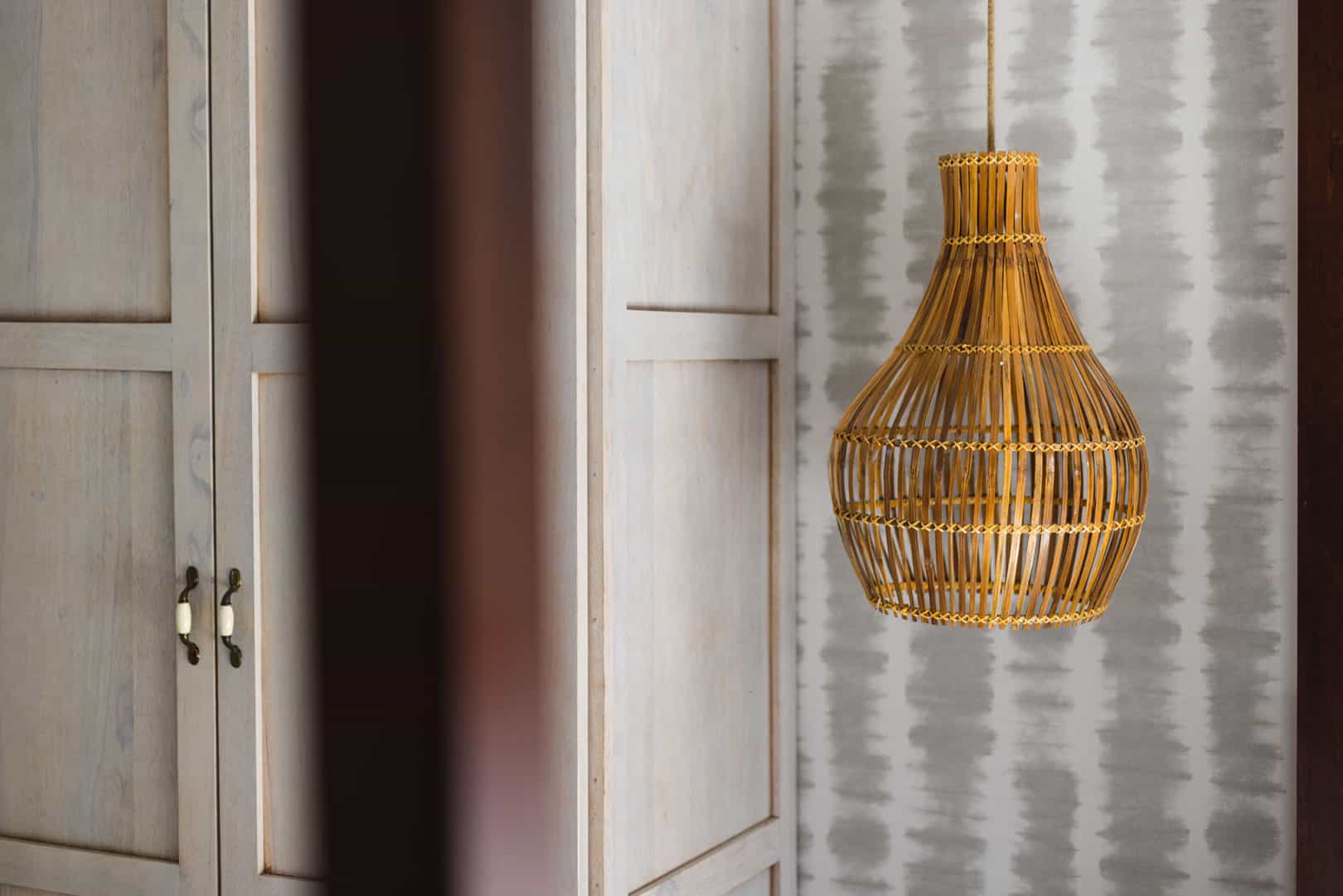 Hand crafted straw lamp and white wooden closet inside of the master bedroom of the Seafront Suite at The Lodge at Jaguar Reef Resort