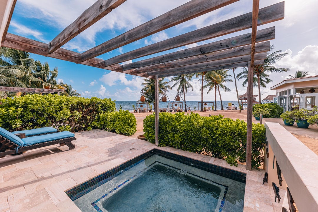 Tiled outdoor patio with two lounge chairs and a plunge pool at the Seafront Suite at The Lodge at Jaguar Reef Resort