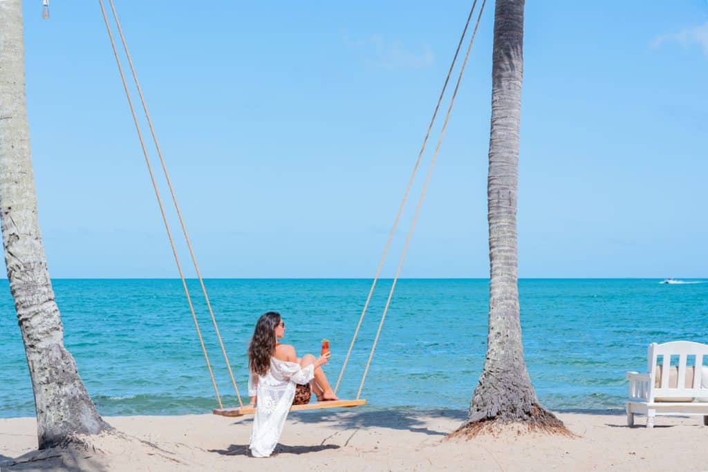 A guest sitting on a swing while looking at the beach at The Lodge at Jaguar Reef Resort