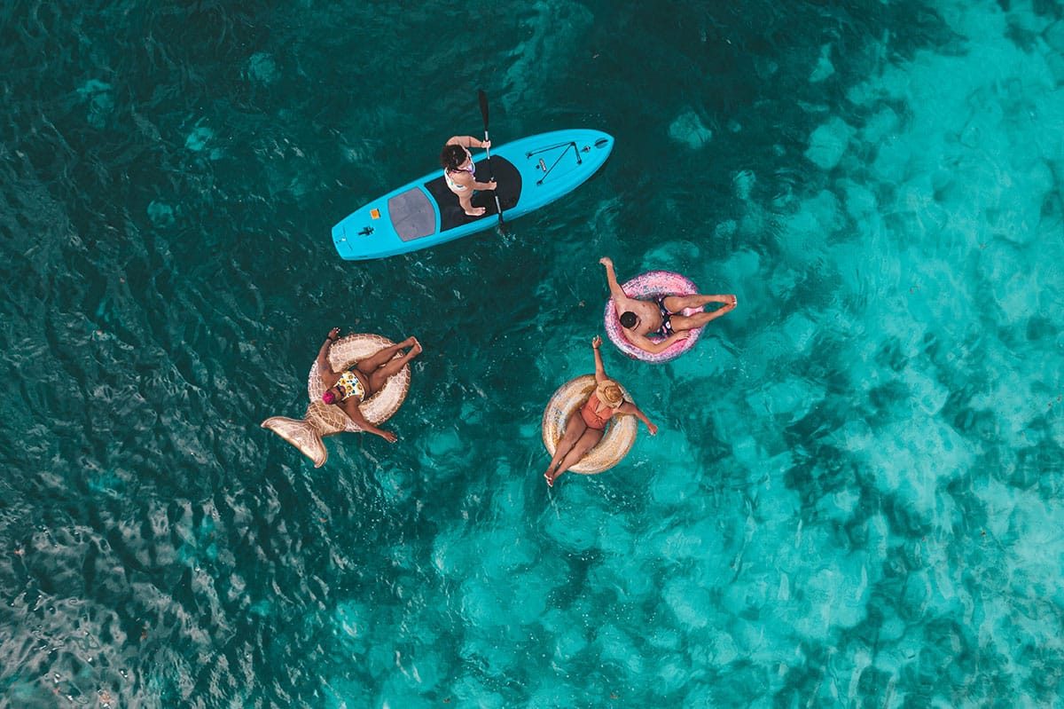 Guests floating in the waters off the shore of Rhythm Reef Caye by The Belize Collection